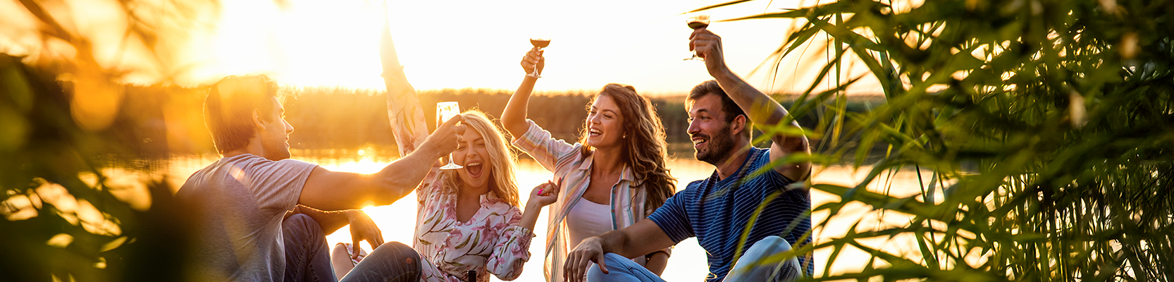 Feiernde Menschen mit Weingläsern am See