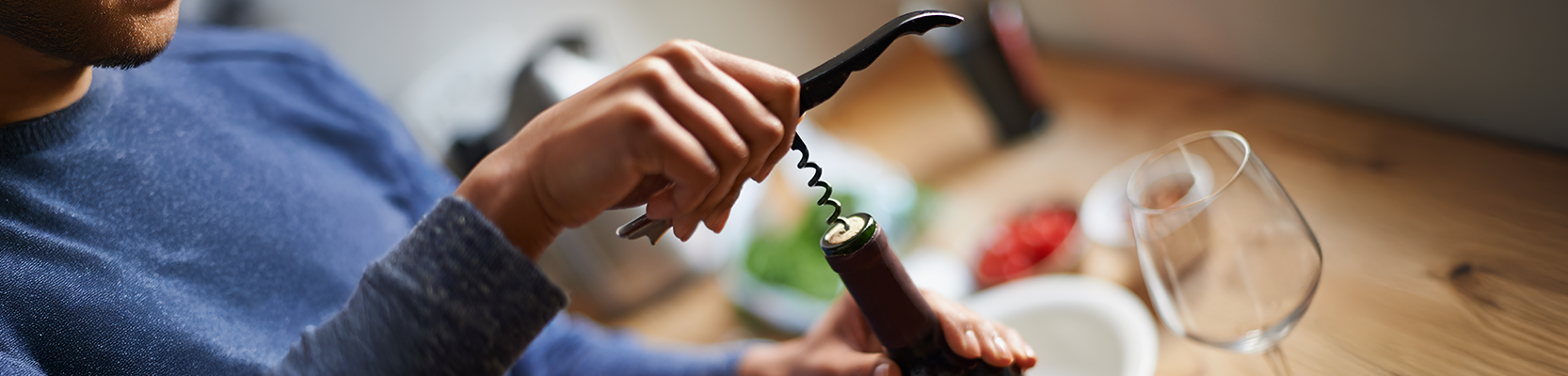 Weinflasche wird von Korkenzieher geöffnet.