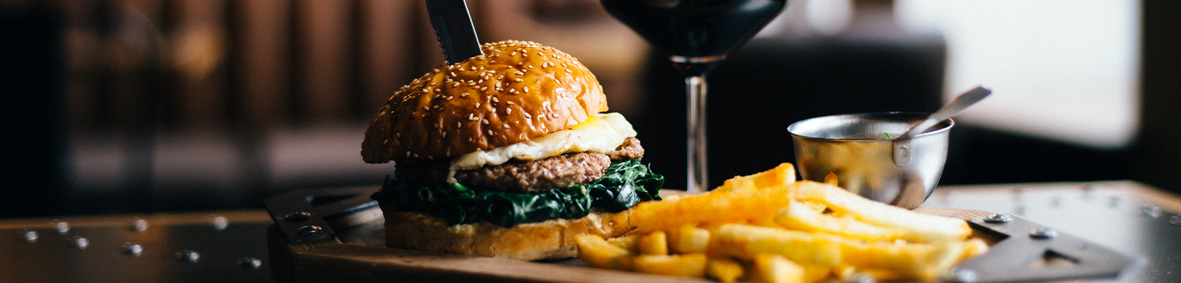 Burger mit Pommes und einem Glas Rotwein